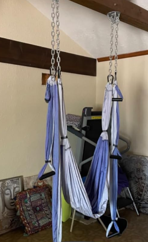 Two aerial yoga swings hanging from ceiling hooks indoors